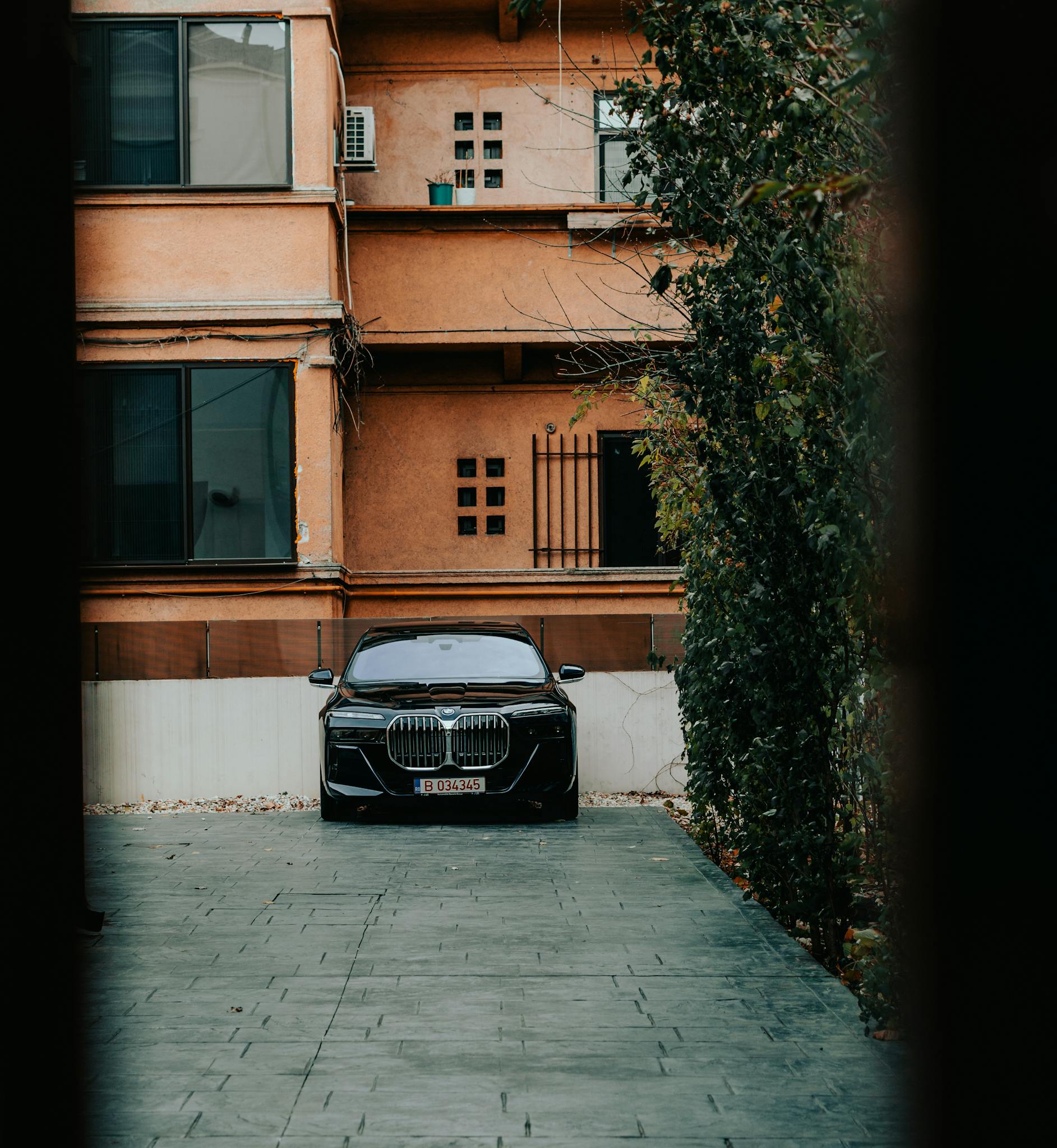 Black luxury BMW parked in front of a modern apartment building in urban Bucharest.