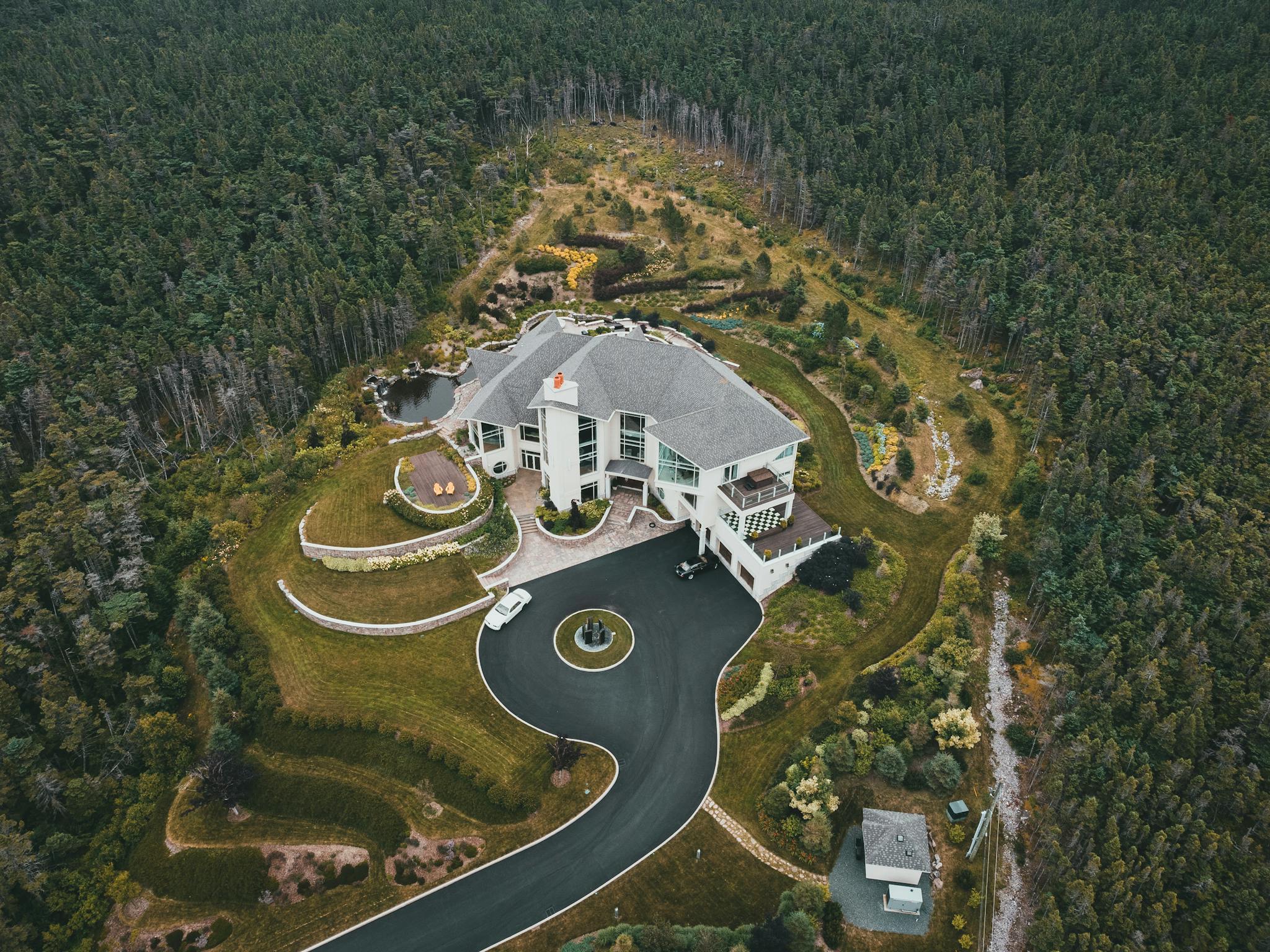 Drone shot of a luxurious house surrounded by dense forested landscape.